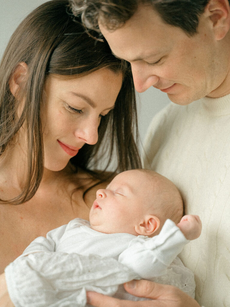 mom and baby snuggle together with father