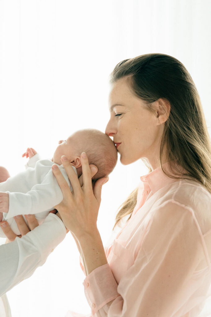 mother kisses baby son on the top of the head