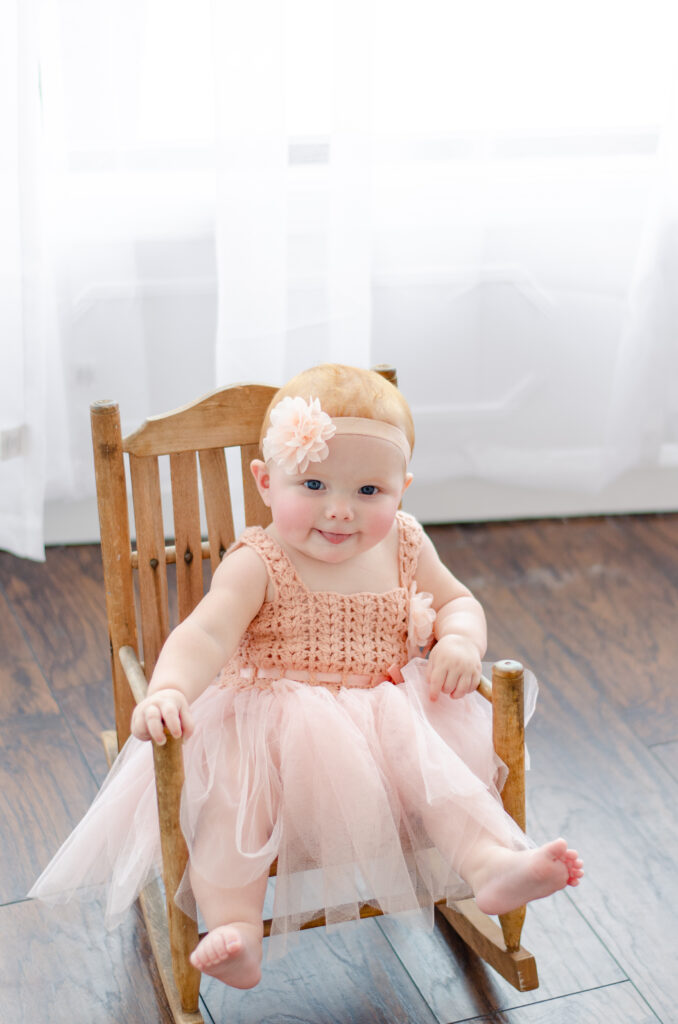 baby in roze jurk in stoeltje