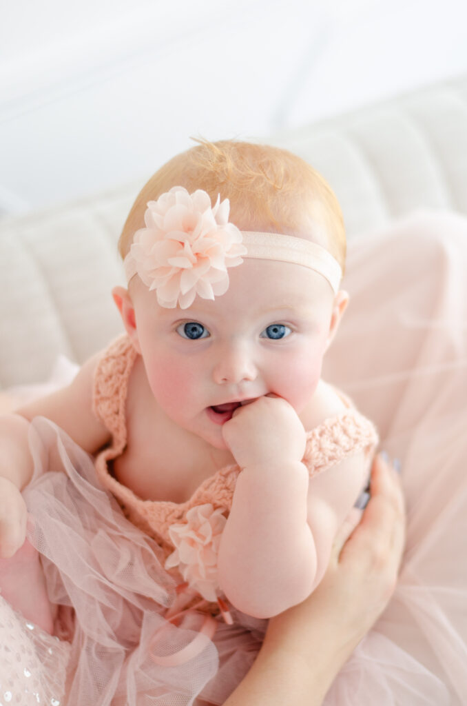 roodharige baby met blauwe ogen in roze jurk