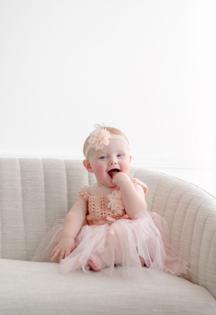 little girl sits on the couch with a pretty pink dress 