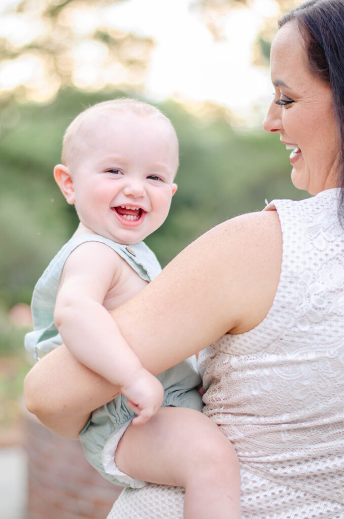 baby laughing on mom's hip in a garden for family photos by amsterdam photographer
