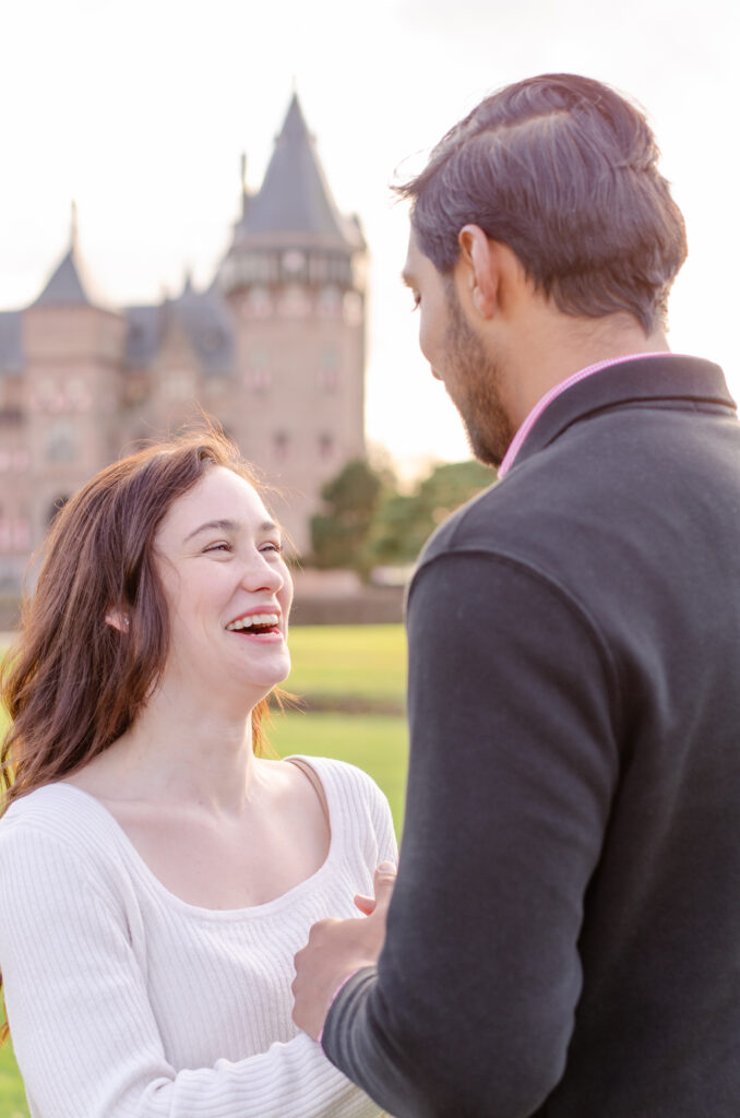 couple laughs together at a castle for engagement portraits