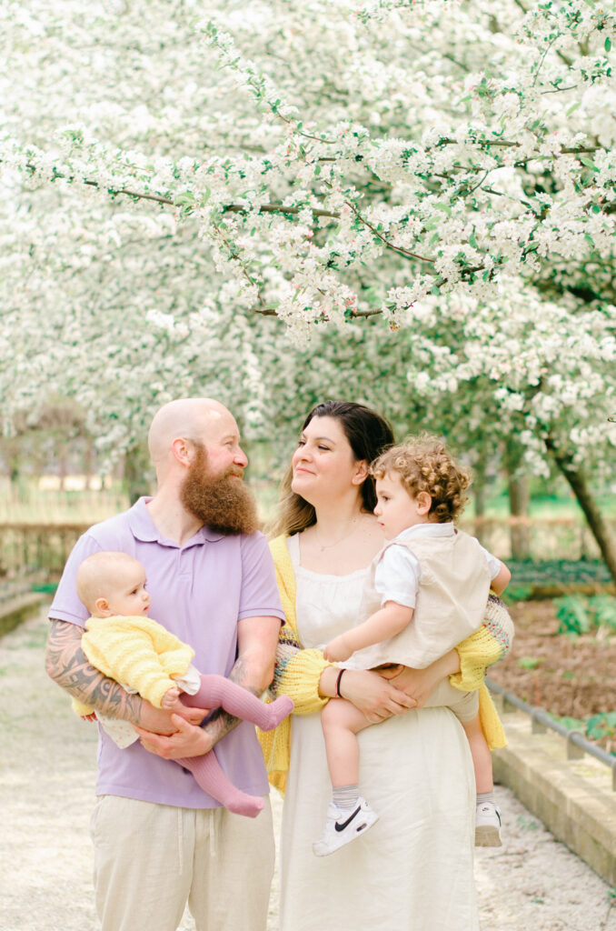 Husband and wife exchange an admiring glance while they hold their children.