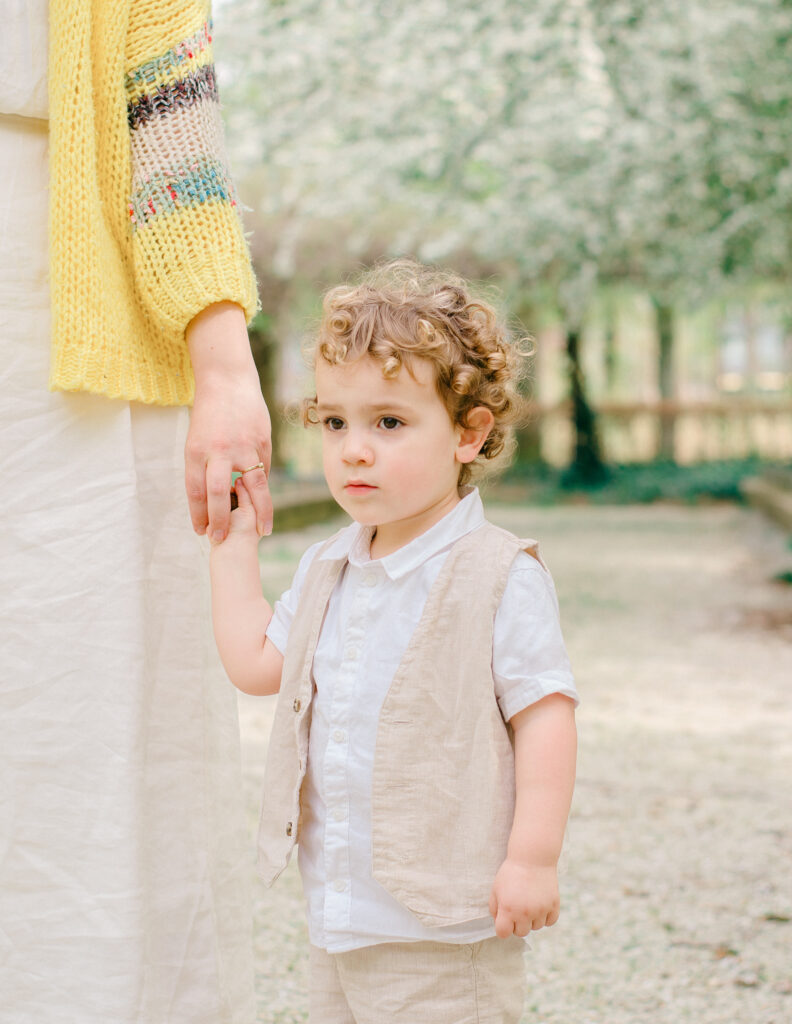 A little boy with soft golden curls holds his mother's hand.