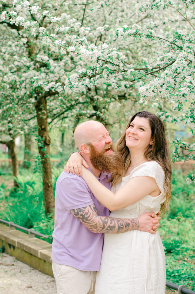 Husband and wife laugh together in a park.