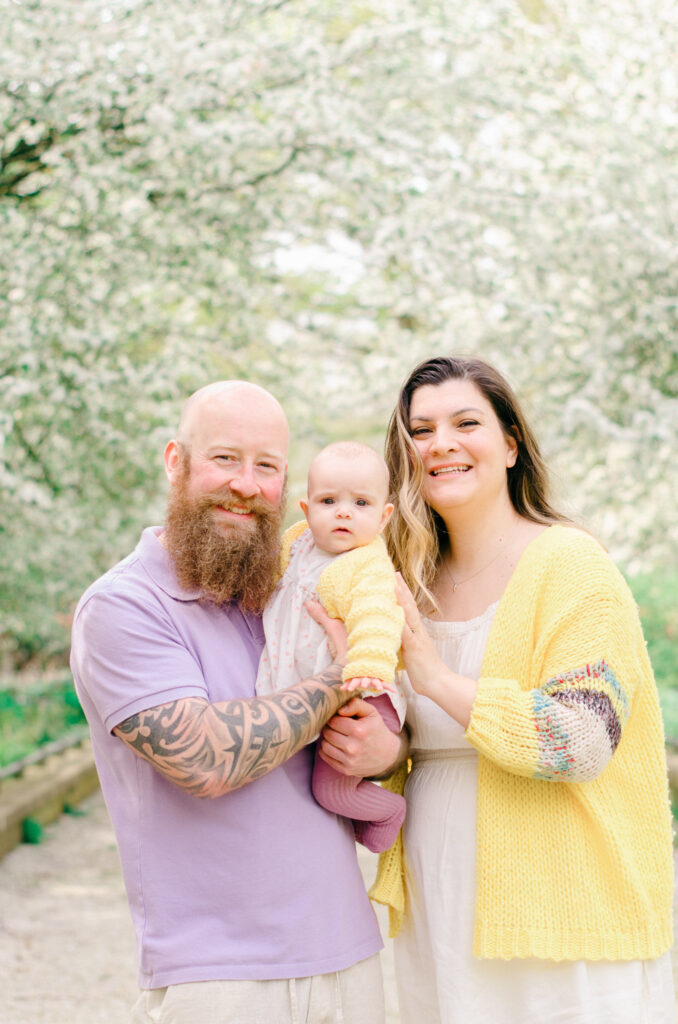 A couple holds their youngest daughter and smiles.