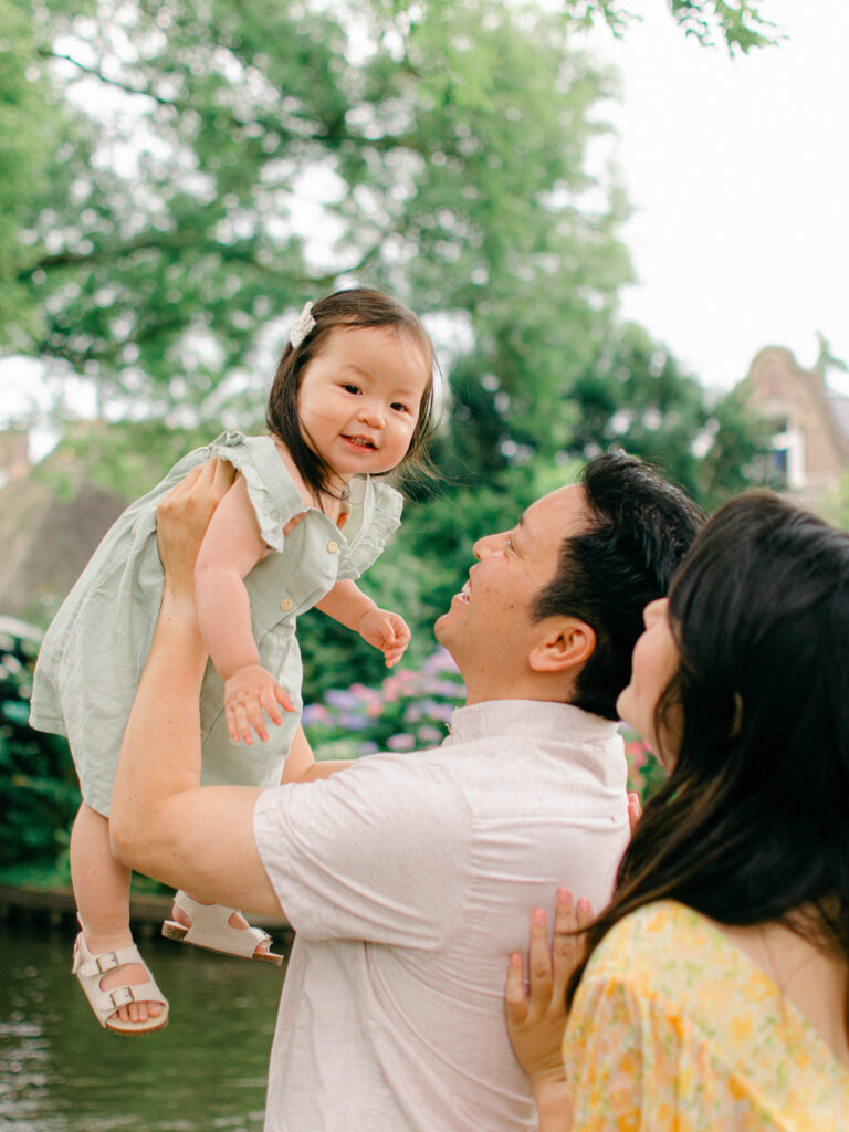 Father lifts toddler daughter up into the air in Giethoorn.