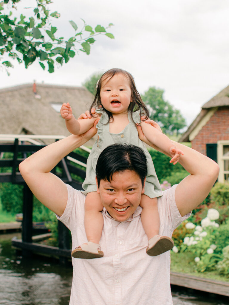 Father carries his daughter on his shoulders so she can reach the blooms in Giethoorn.