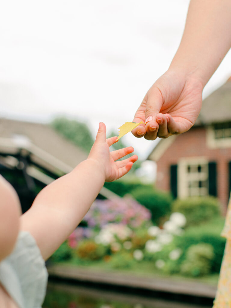 Father hands daughter a little yellow leaf by the canals.