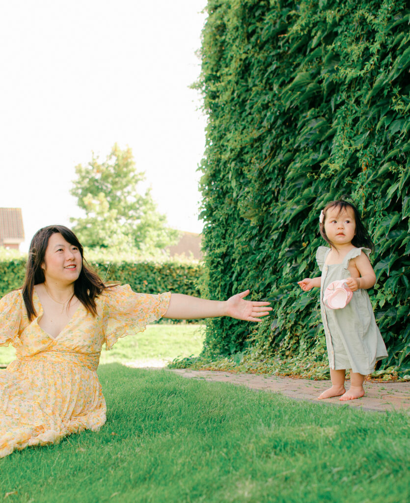 Mom holds hand out to infant daughter.