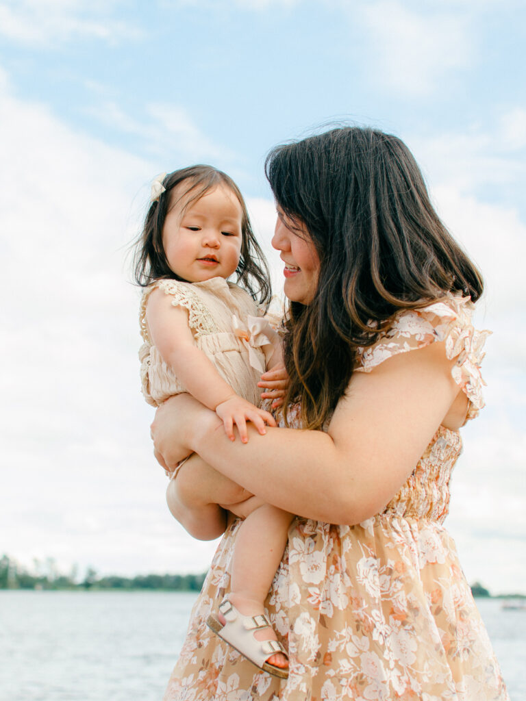 Mom and infant daughter, both in beige, snuggle by the water at Giethoorn.