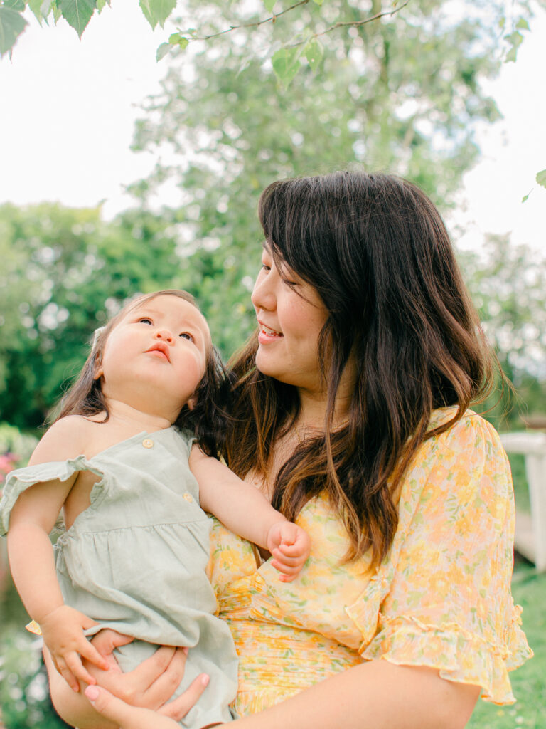 Toddler daughter looks up into the sky with her mom.
