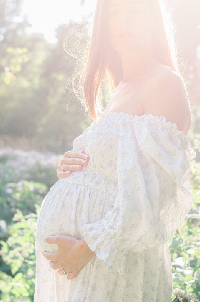 Silhouette of expectant mother in golden afternoon light.