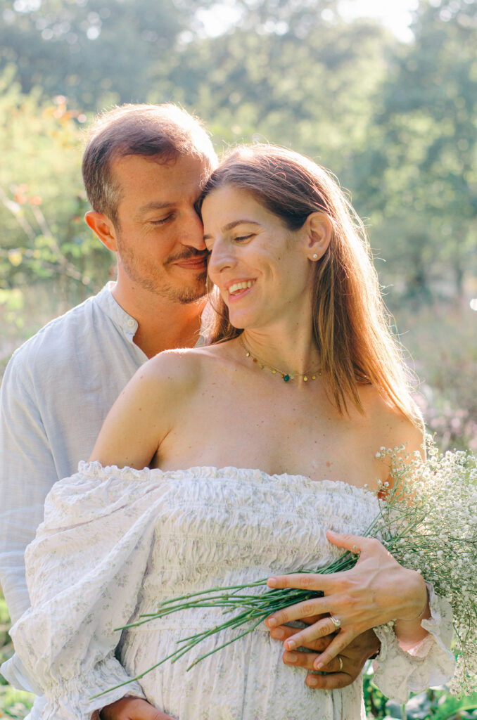 Mom and dad-to-be snuggle up in an Amsterdam garden in the summer.