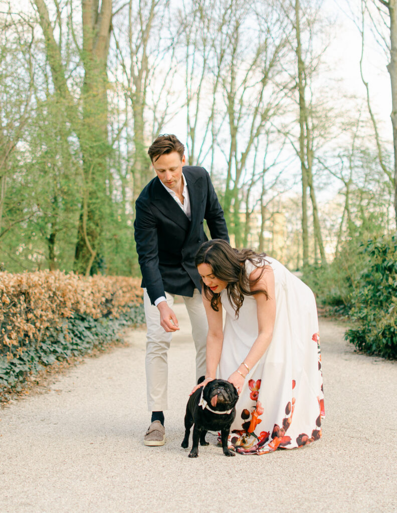 Expecting mother bends down to pet bulldog.