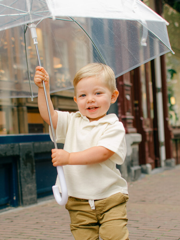 Toddler son runs around with a clear umbrella, happy and excited.