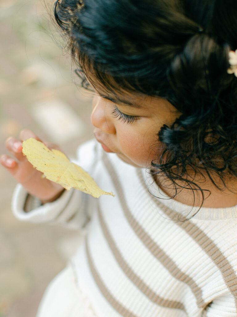 Soft and elegant detail image of a child looking at a leaf in Amsterdam.