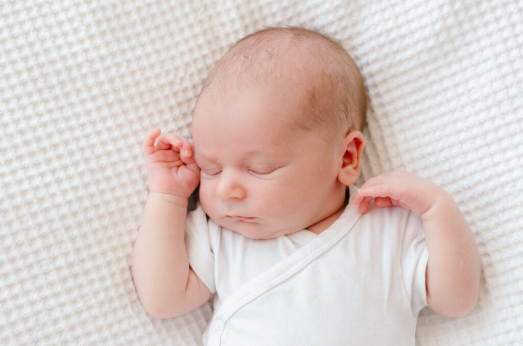 Newborn baby sleeping on a white blanket in a minimalist studio in Amsterdam.