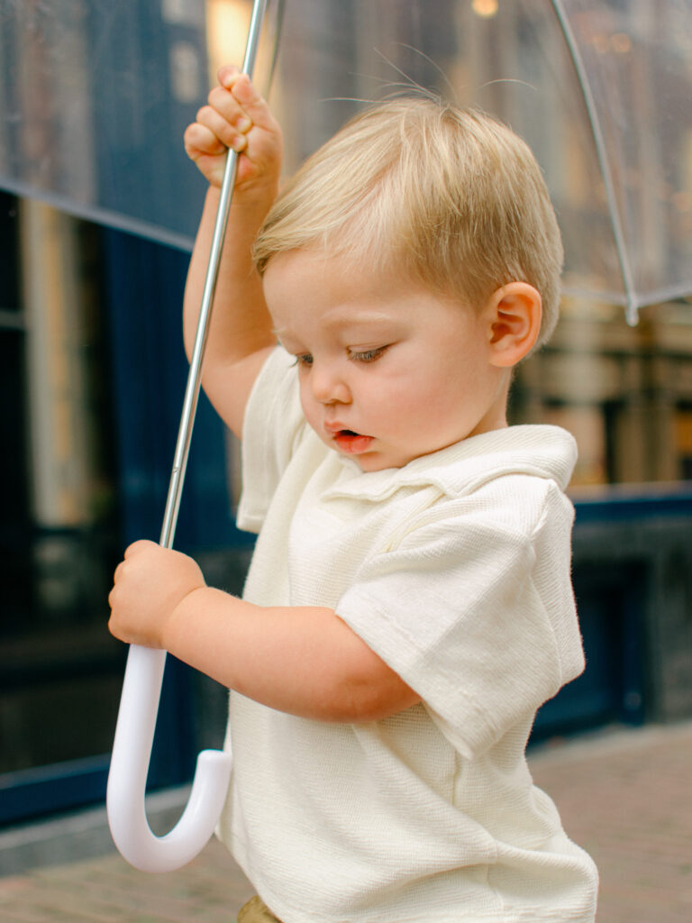 Lifestyle image of a little boy with an umbrella in the streets of Amsterdam.