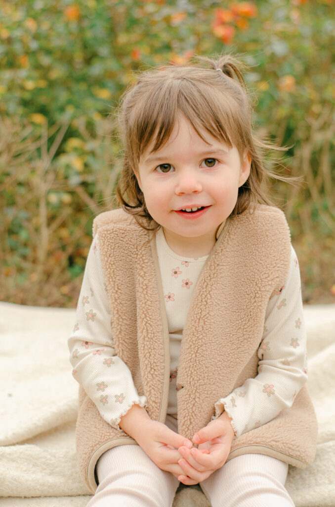 Toddler smiling on a blanket in the fall in Vondelpark.