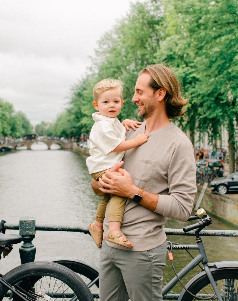 Father holds his toddler son on a canal bridge in Amsterdam.