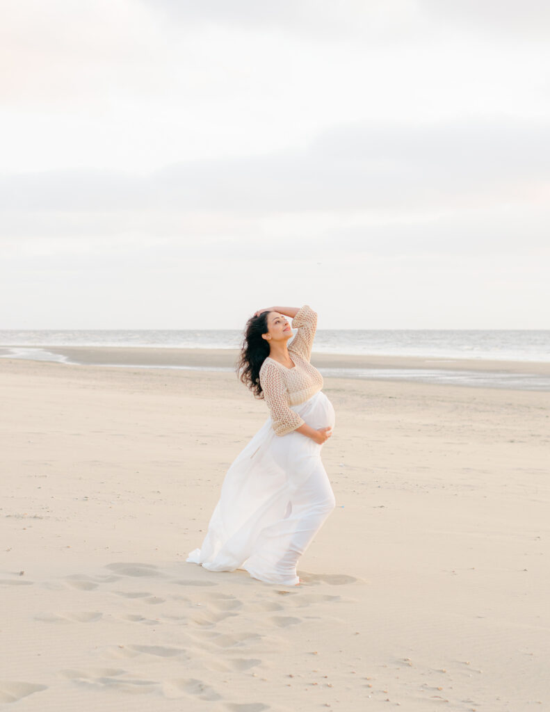 Pulled back image of an expecting mama on the Bloemendaal beach at sunset.