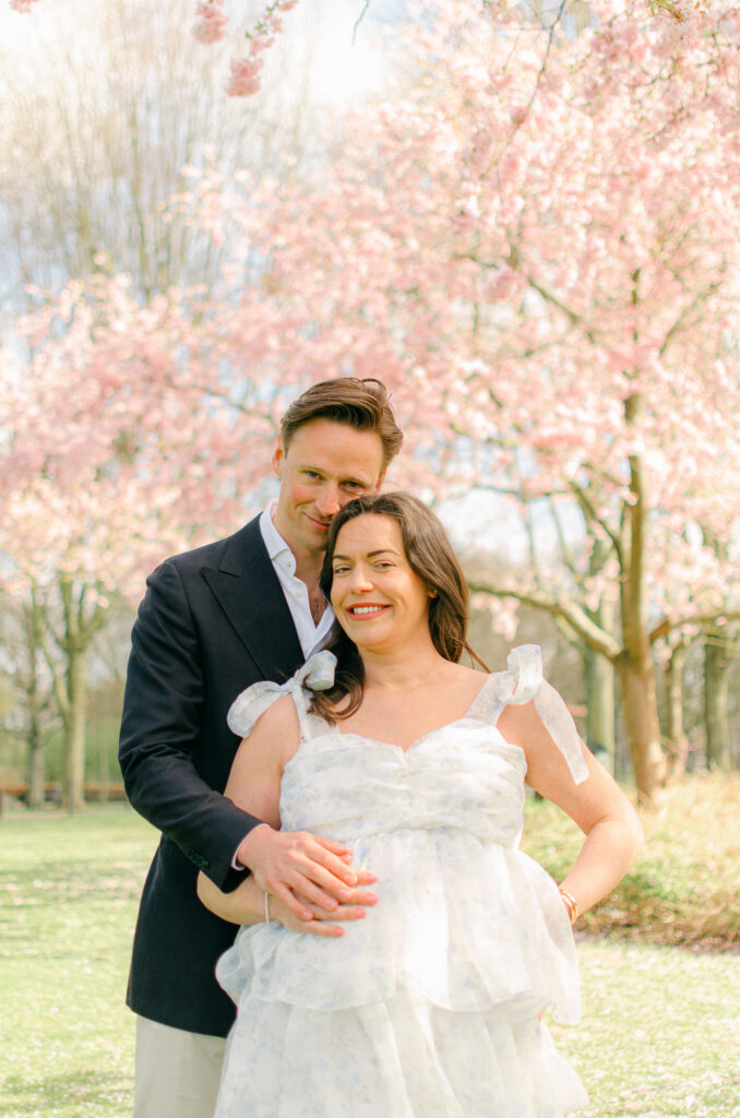 Happy parents-to-be smiling and holding baby bump.