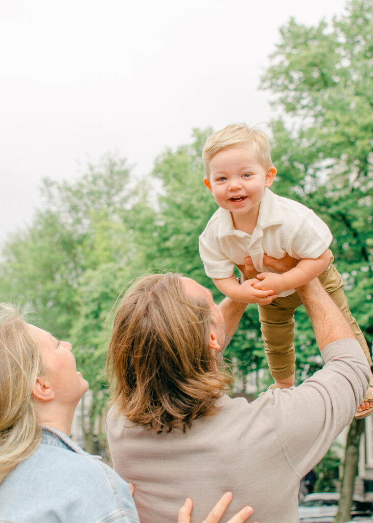 Family holds their toddler son up on a bridge in Amsterdam, near Keizersgracht.