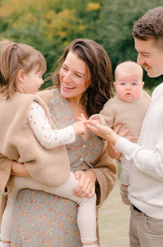 Parents holding children during cozy autumn moment.