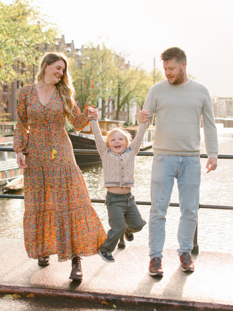 Parents swinging son on an Amsterdam bridge in the Jordaan district.