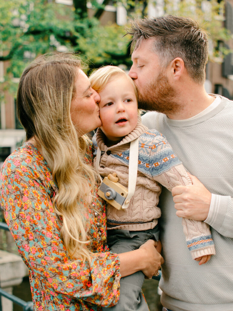 Parents give son a kiss while playing in Amsterdam.