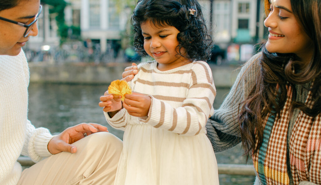 Toddler playing with fallen leaves near the Keizersgracht canal.