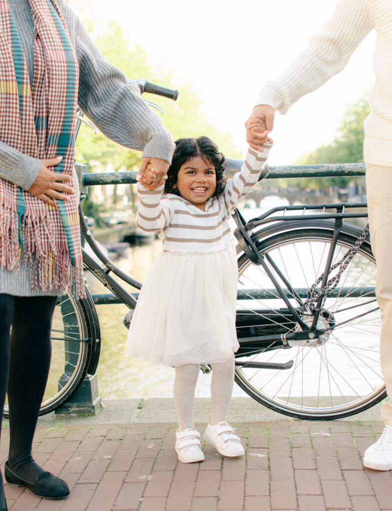 Toddler swings between her parents on an Amsterdam bridge.