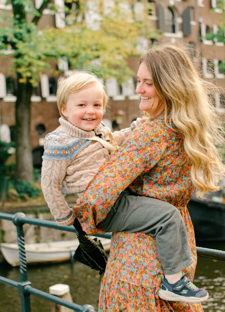 Mum swings toddler around during a family session in Jordaan.
