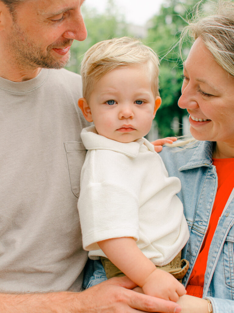 Fine art image of a toddler in his parent's arms.