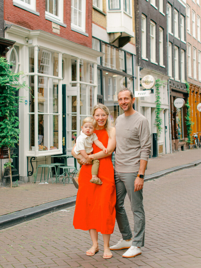Parents hold toddler son on the cobblestone streets of Amsterdam.
