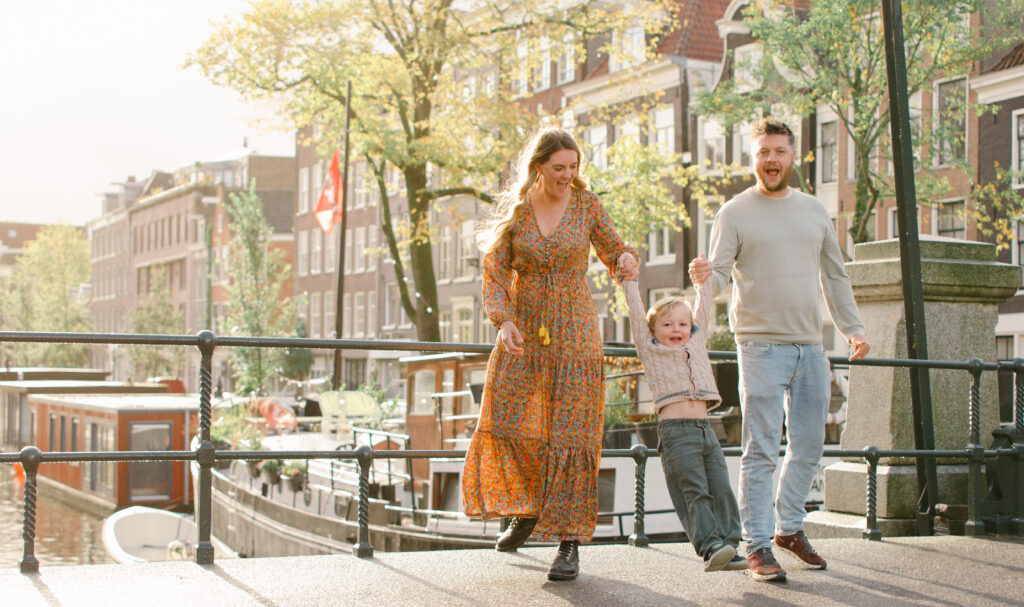 Family standing on a bridge in Jordaan in the early morning sun.