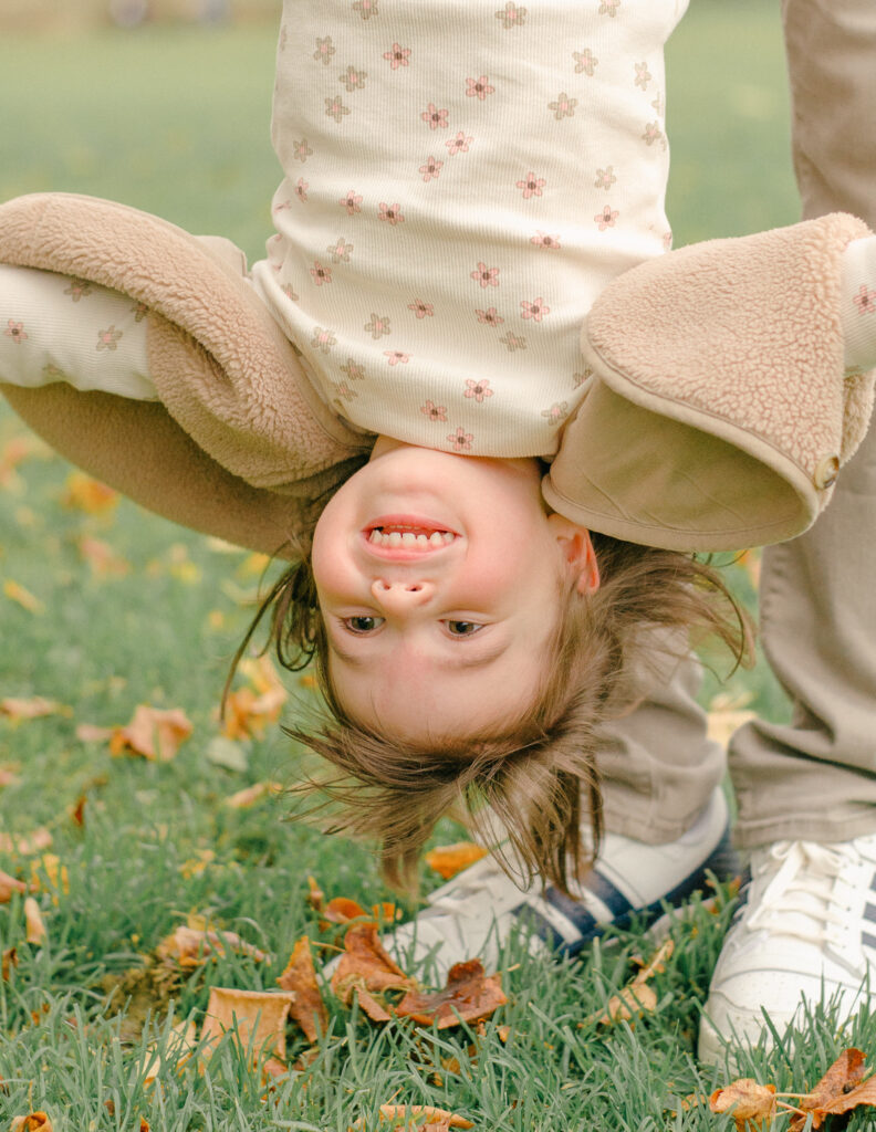 Parents hold young daughter upside down during a fun family photo session.