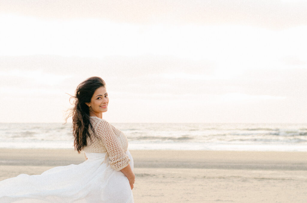 Soft-focus lifestyle image of an expecting mother on the Bloemendaal beach at sunset.