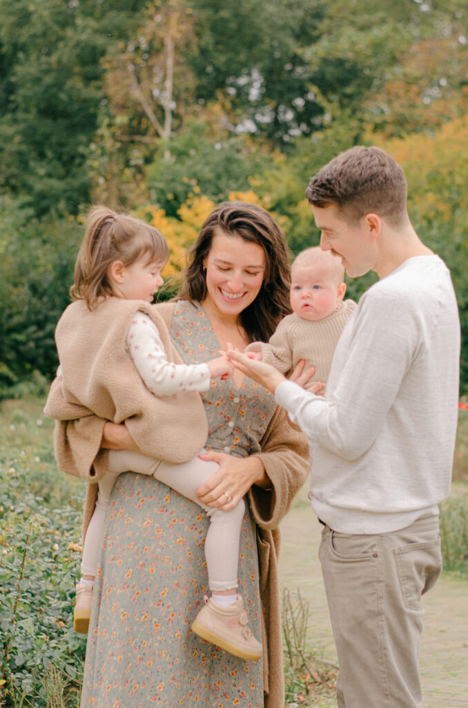 Candid image of parents showing their daughters a fall leaf.
