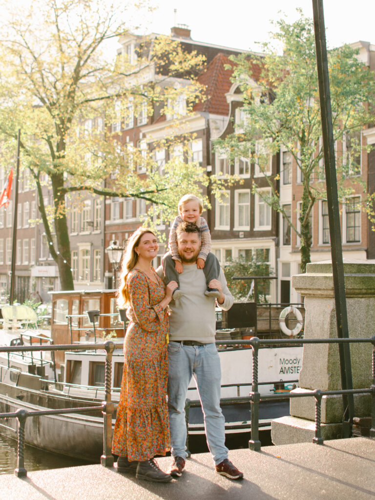 Family of three smile for a picture on a bridge in Jordaan.