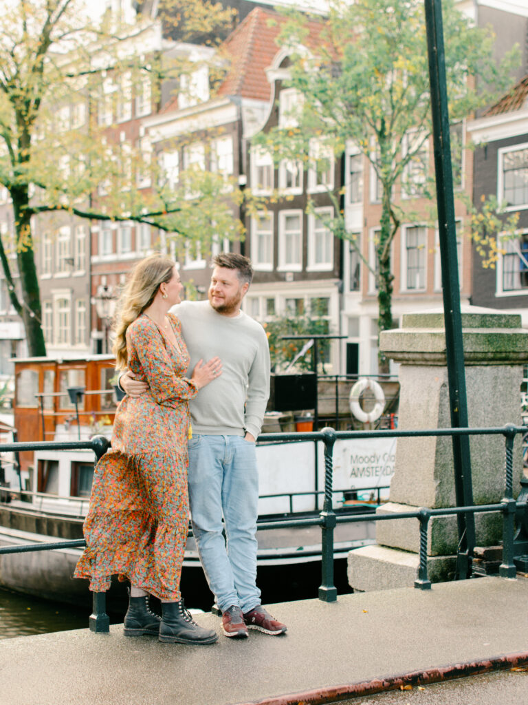 Husband and wife embrace on a bridge in the Jordaan area.
