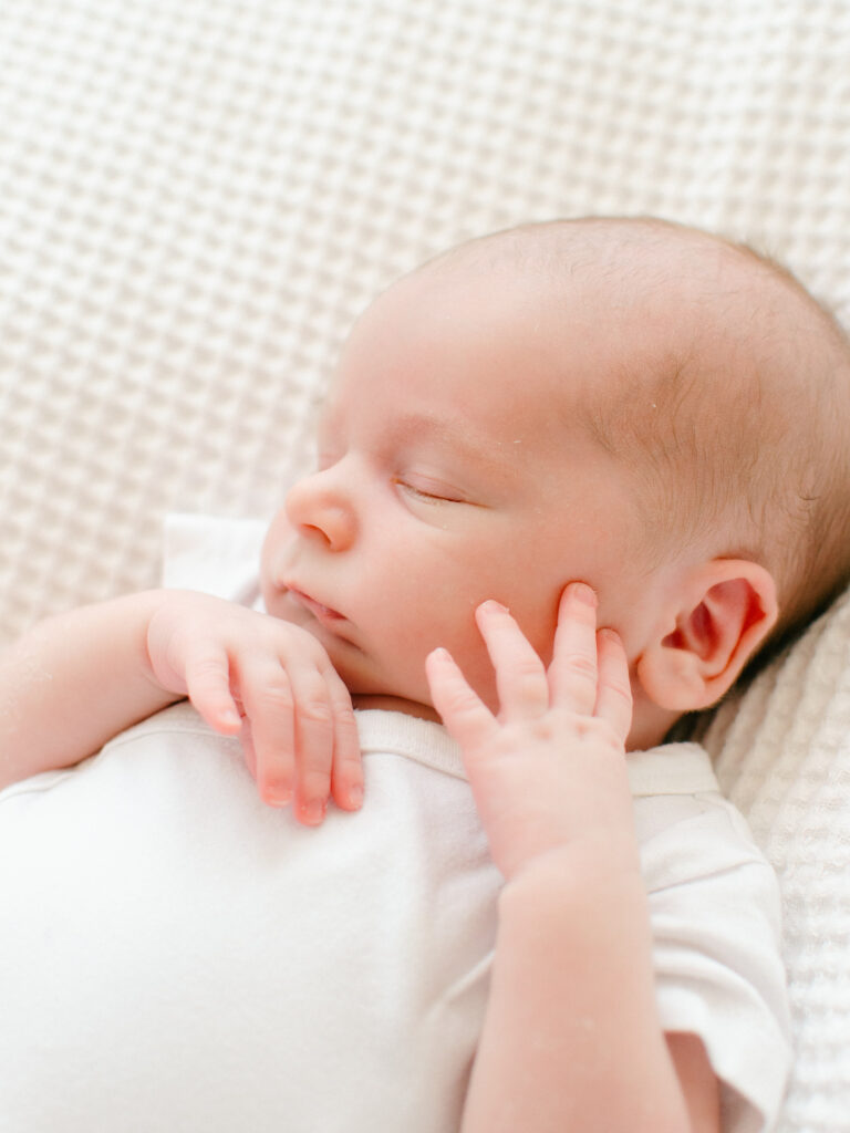 Elegant photo of newborn boy sleeping on a textured white blanket.