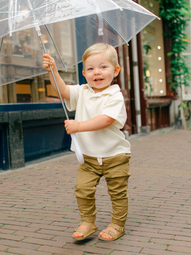 Toddler boy is so happy and runs around with an umbrella in Amsterdam.