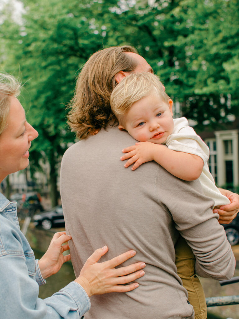 Mom plays peek-a-boo with toddler son in Amsterdam Nine Streets.