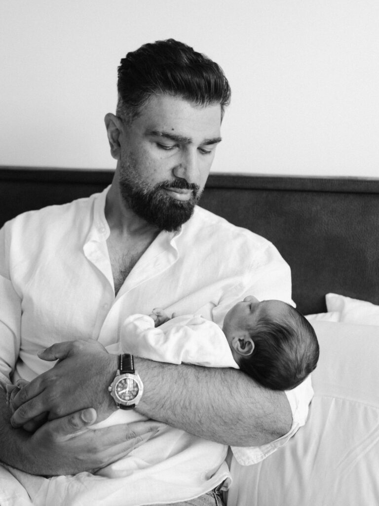 Father gazes lovingly at his newborn son during a lifestyle photo session.