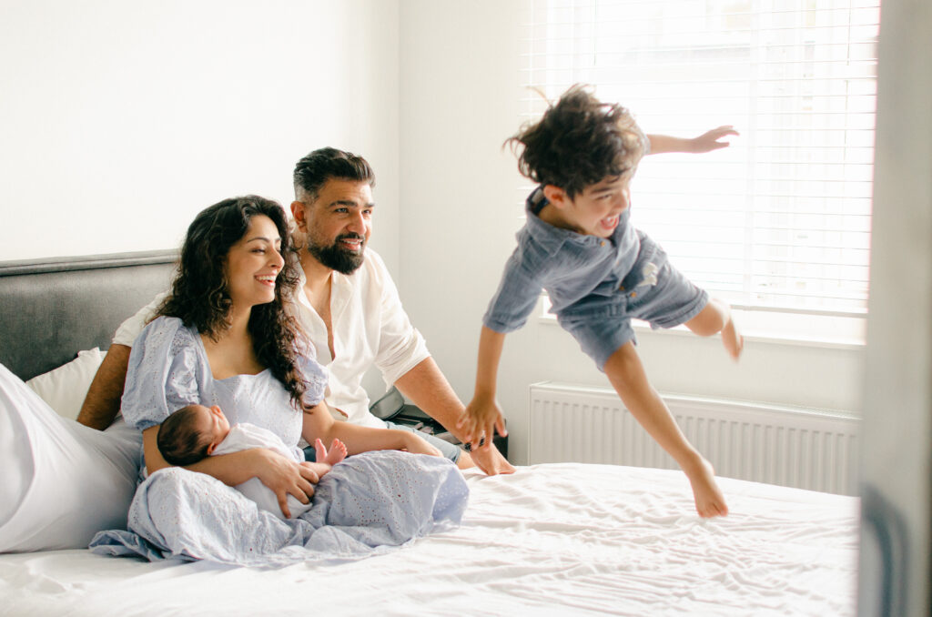 Mid-jump image of toddler enjoying his brother's newborn session.