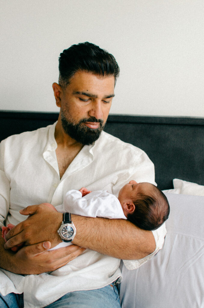 Father looking at baby lovingly during in-home shoot.