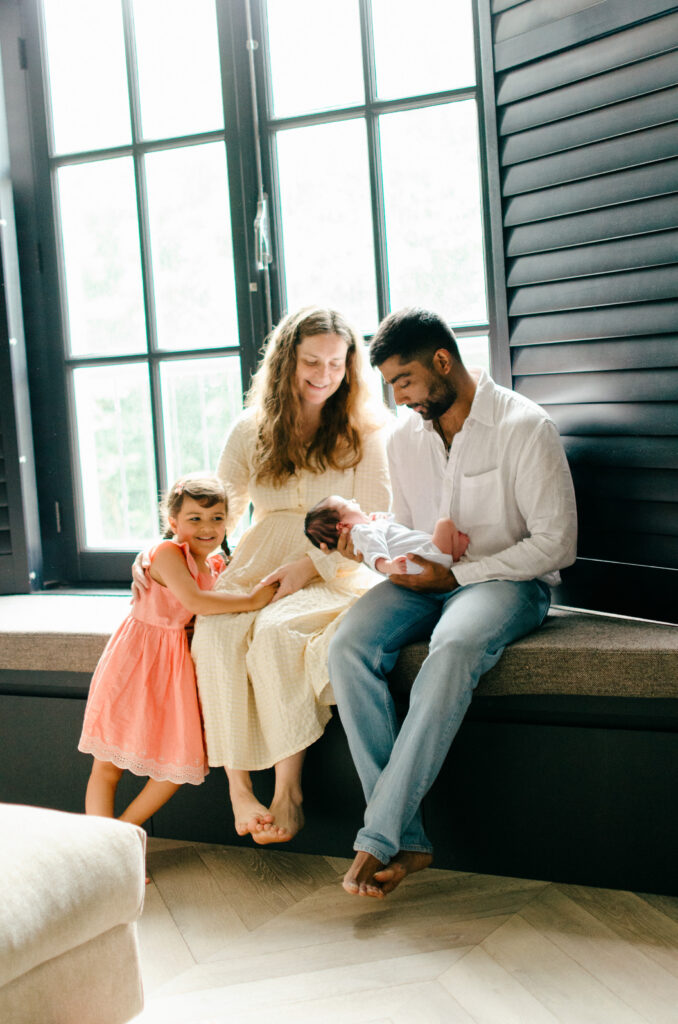 A family of four sits on a windowsill in their home in Oud-West during a photoshoot.